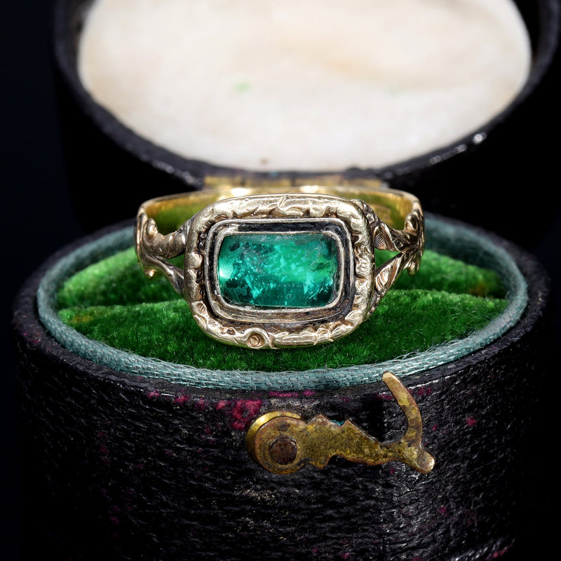 Georgian foil-backed green paste ring in gold, dated 1822, with a vivid green paste stone in a closed-back rubover setting and foliate scroll shoulders