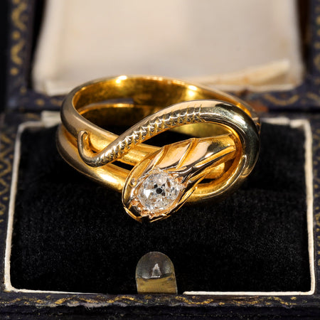 Antique Victorian coiled snake ring in yellow gold with an old cut diamond set in the serpent's head, displayed in a period ring box