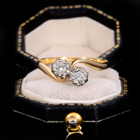 Vintage toi et moi diamond ring with two brilliant cut diamonds in white metal claw settings on a yellow gold crossover band, stamped 18ct