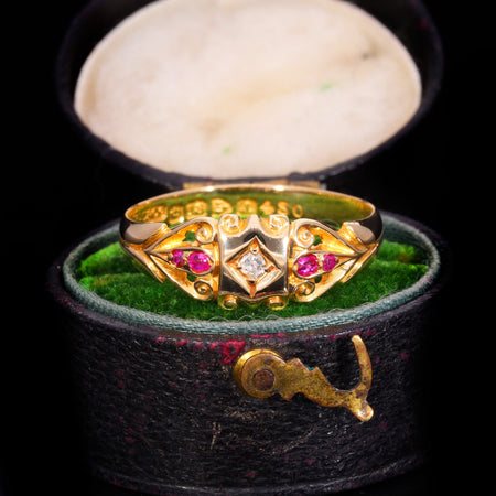 Edwardian diamond and ruby scroll ring in 18ct yellow gold, hallmarked 1901, with scrollwork shoulders and central diamond flanked by rubies