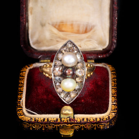 Georgian navette ring with three natural pearls surrounded by rose cut diamonds in a marquise-shaped bezel with gold and silver mounting, displayed in an original antique ring box