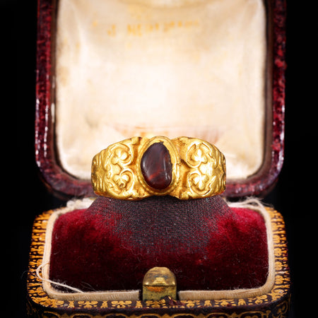 Ancient Roman gold ring set with a garnet cabochon and engraved clover motifs on the shoulders, circa 2nd-3rd century