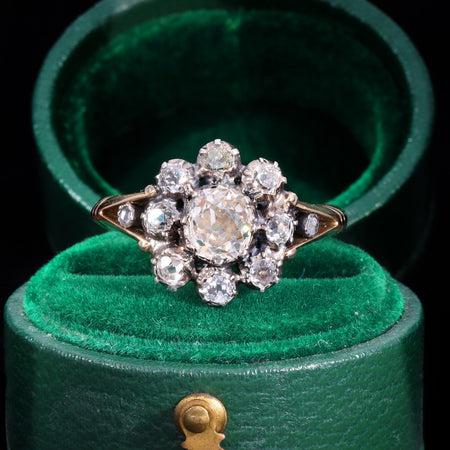 Georgian eleven-stone diamond cluster ring in gold with old European cut diamonds arranged in a daisy pattern around a larger central stone