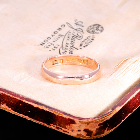 Antique Victorian 1871 rose gold wedding ring showing hallmarks stamped inside the band, displayed on a vintage jeweller's box